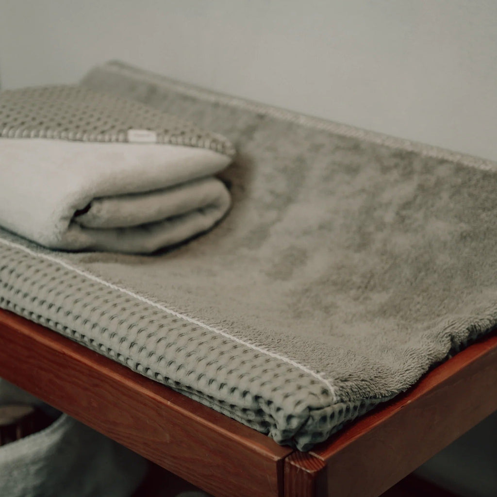 Koeka Omslagdoek Wafel/Teddy Oslo in olive opgevouwen in de babykamer