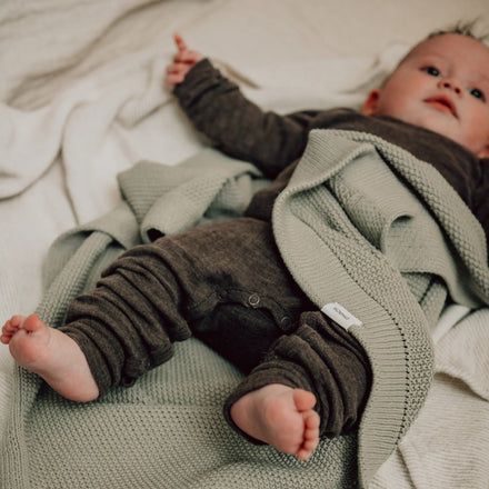 Koeka Wiegdeken Lisbon in olive bij een baby op bed