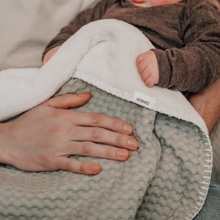 Koeka Wiegdeken Wafel/Teddy Oslo in olive over een baby heen