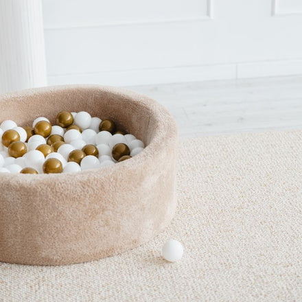 Moje ballenbad Teddy beige op een vloerkleed met losse ballen ernaast
