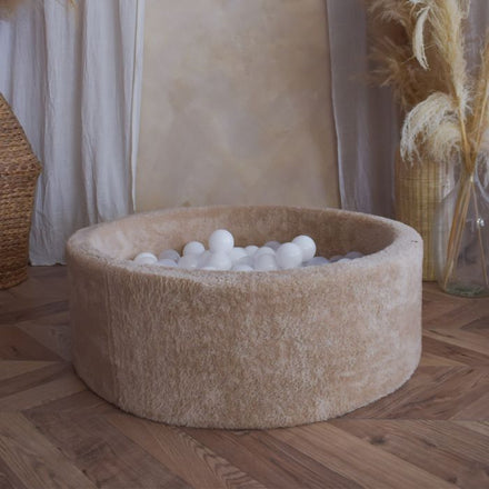 Moje ballenbad Teddy beige gevuld met witte ballen in een warme woonkamer