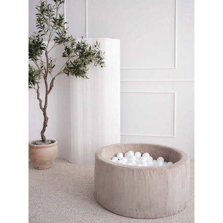 Moje ballenbad Velvet Rib beige met witte ballen naast een plant