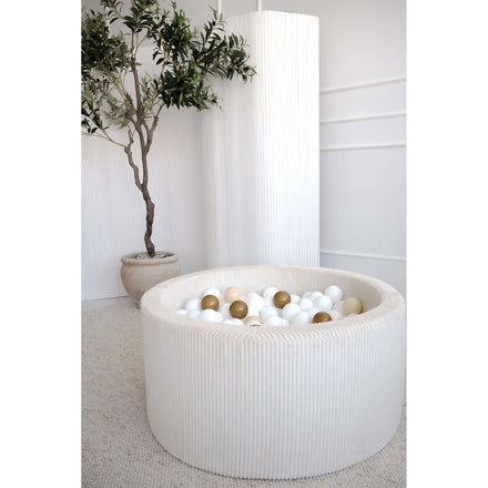 Moje ballenbad Velvet Rib cream met witte en gouden ballen naast een plant