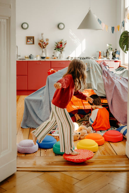 Stapelstein Winter Special Rainbow Set Classic, kind speelt met de stenen voor een hut in de woonkamer